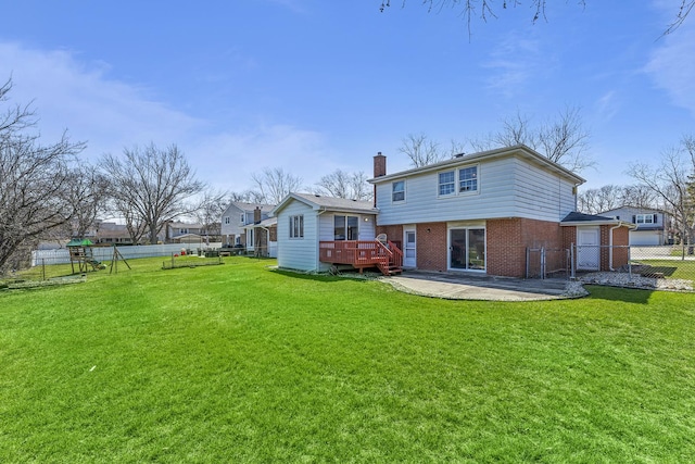 back of property with a chimney, a fenced backyard, a yard, a wooden deck, and brick siding