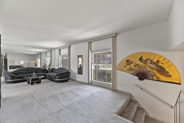 carpeted living area with stairway, a wealth of natural light, and baseboards