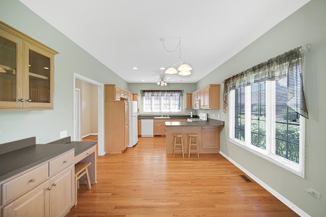 9154 Arbour Walk Dr, Frankfort, IL 60423 - kitchen featuring white appliances, a peninsula, light wood-type flooring, light brown cabinets, and a breakfast bar