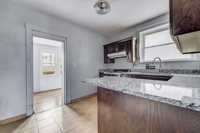 5048 W Wrightwood Ave, Chicago, IL 60639 - kitchen featuring under cabinet range hood, dark brown cabinetry, light stone counters, white range with gas stovetop, and light tile patterned floors