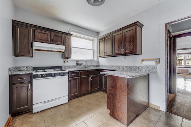 5048 W Wrightwood Ave, Chicago, IL 60639 - kitchen featuring white gas stove, under cabinet range hood, dark brown cabinets, and light stone counters