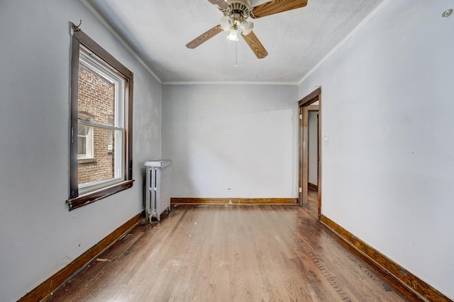 5048 W Wrightwood Ave, Chicago, IL 60639 - spare room with radiator heating unit, wood finished floors, a ceiling fan, and ornamental molding