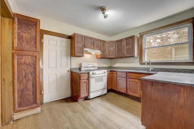 5048 W Wrightwood Ave, Chicago, IL 60639 - kitchen featuring white gas stove, under cabinet range hood, light wood finished floors, stone counters, and brown cabinetry