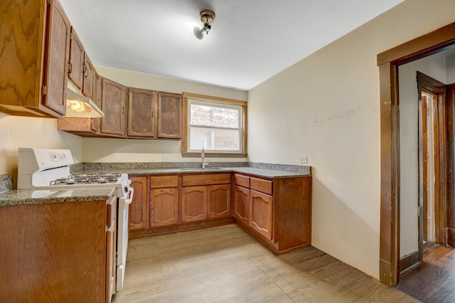 5048 W Wrightwood Ave, Chicago, IL 60639 - kitchen featuring white range with gas cooktop, under cabinet range hood, light wood finished floors, and brown cabinetry