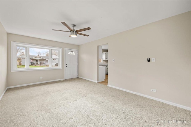 unfurnished living room featuring baseboards, a ceiling fan, and light colored carpet