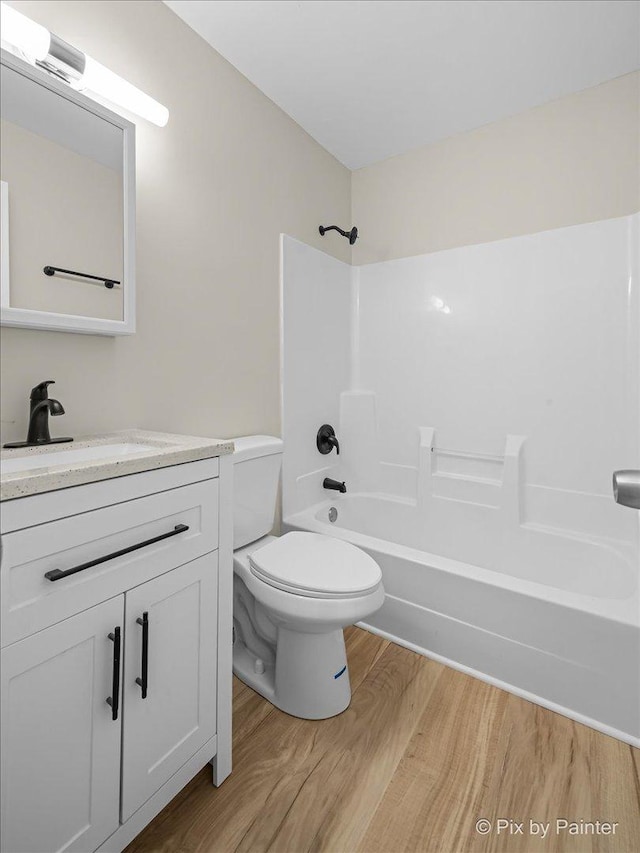 bathroom featuring toilet, shower / tub combination, vanity, and wood finished floors