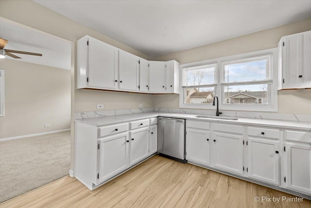 kitchen featuring white cabinets, baseboards, a sink, ceiling fan, and stainless steel dishwasher