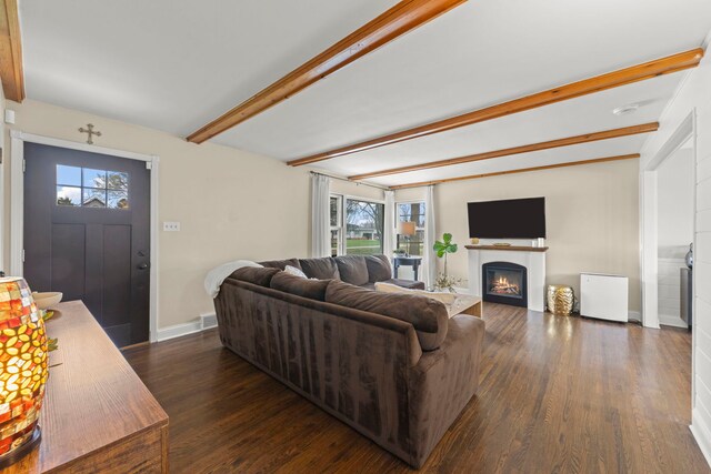 living room with dark wood-style flooring, baseboards, beamed ceiling, and a warm lit fireplace