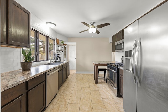 kitchen featuring dark brown cabinetry, tasteful backsplash, a ceiling fan, appliances with stainless steel finishes, and a sink
