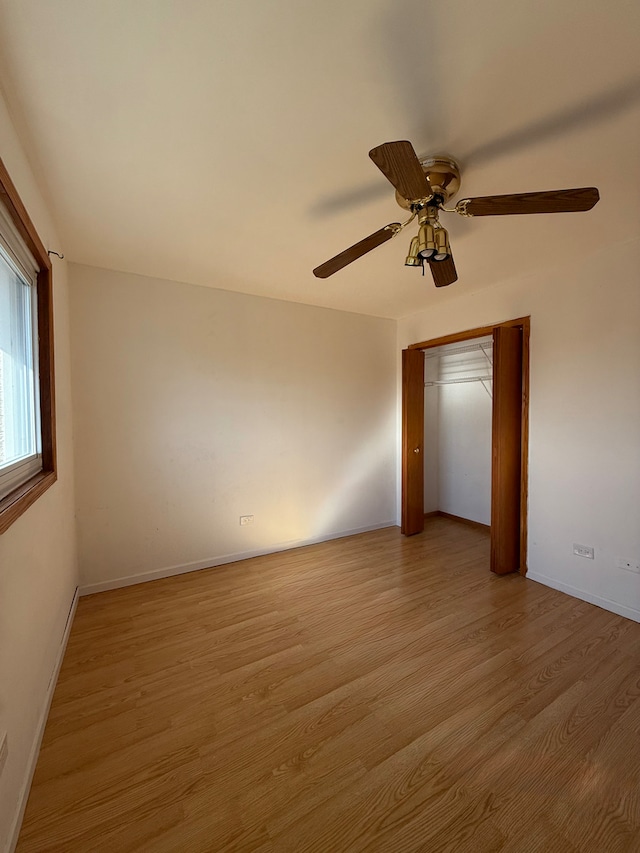 spare room with baseboards, light wood finished floors, and a ceiling fan