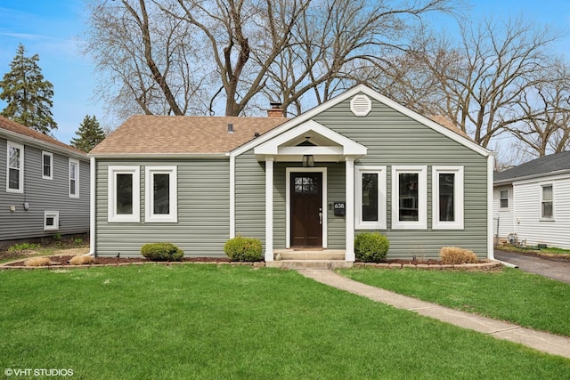 bungalow-style home featuring roof with shingles, a chimney, and a front lawn