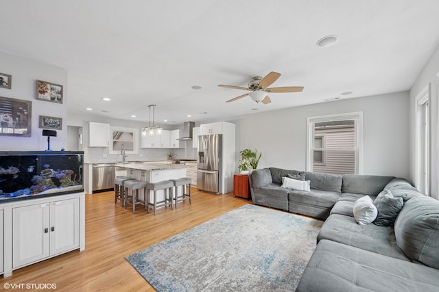 living area featuring ceiling fan, light wood finished floors, and recessed lighting