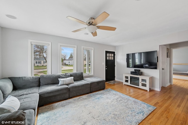 living room with light wood finished floors, baseboards, and ceiling fan