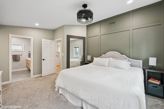 bedroom with a decorative wall, visible vents, recessed lighting, and light carpet