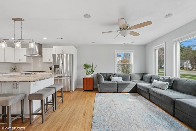 living room with recessed lighting, ceiling fan, light wood finished floors, and baseboards