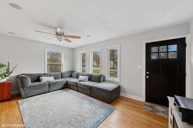 living area with light wood-style floors, baseboards, and a ceiling fan