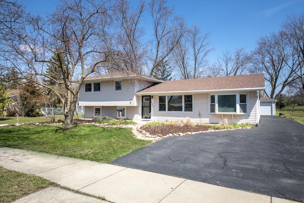 tri-level home featuring a detached garage, an outbuilding, and a front yard