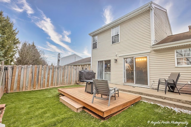 wooden terrace featuring area for grilling, fence, and a lawn