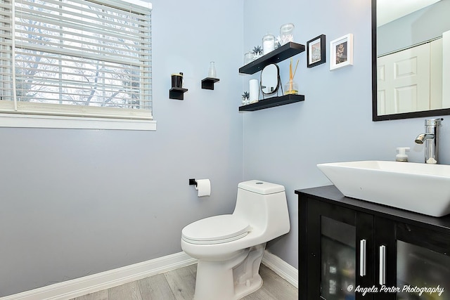 bathroom featuring vanity, baseboards, toilet, and wood finished floors
