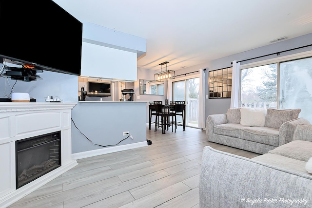 living room with light wood-style floors, a fireplace, and visible vents