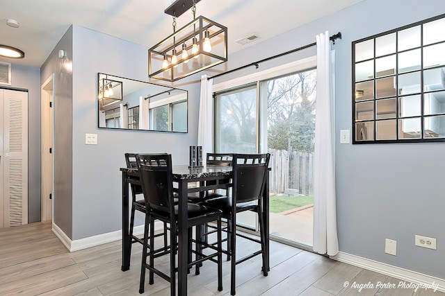 dining space with light wood-style flooring, an inviting chandelier, baseboards, and visible vents