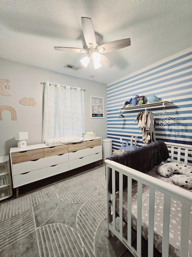 bedroom with a textured ceiling, wallpapered walls, ceiling fan, and visible vents