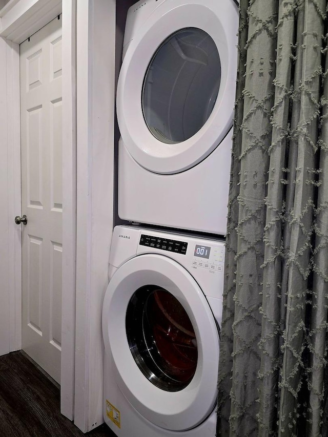 laundry area with stacked washer and dryer, laundry area, and dark wood-style flooring