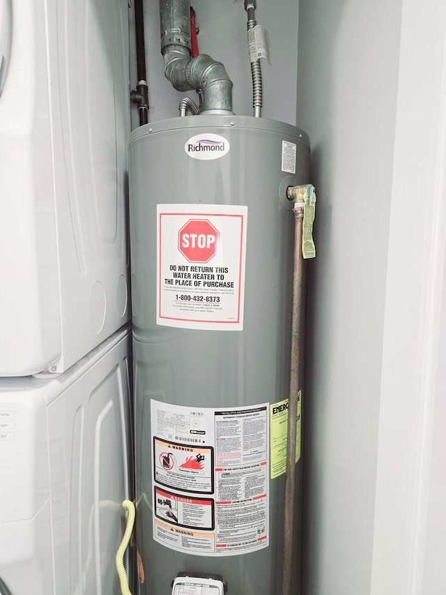 utility room featuring stacked washer / dryer and water heater