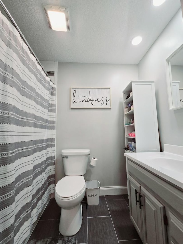 bathroom with vanity, a textured ceiling, baseboards, and toilet