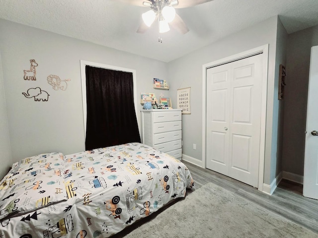 bedroom with a closet, baseboards, ceiling fan, a textured ceiling, and wood finished floors