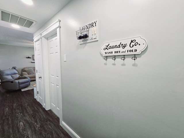 hall featuring dark wood-type flooring, visible vents, and baseboards