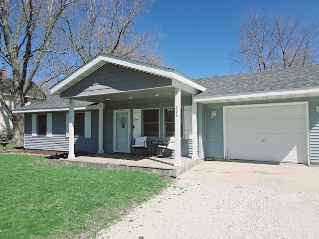 view of front of property with covered porch, roof with shingles, a front lawn, an attached garage, and concrete driveway