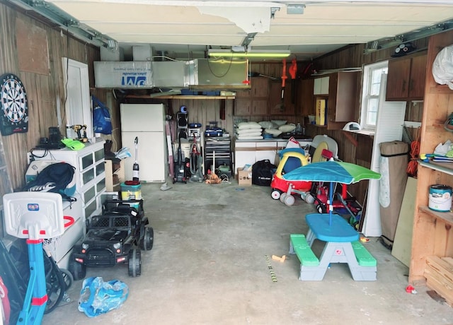 garage featuring wooden walls and freestanding refrigerator