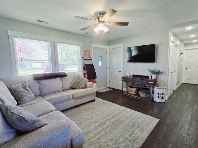 living area featuring ceiling fan, a textured ceiling, visible vents, wood finished floors, and baseboards