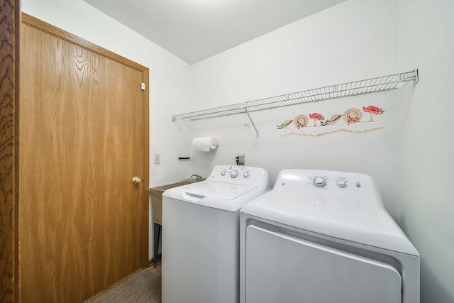 clothes washing area featuring separate washer and dryer, laundry area, and a sink