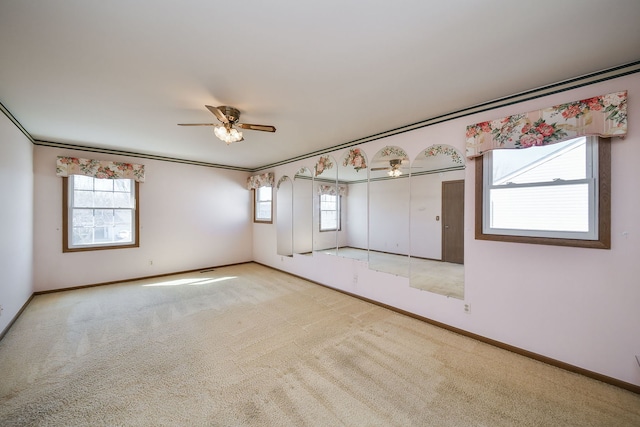 carpeted spare room featuring ornamental molding, ceiling fan, and baseboards
