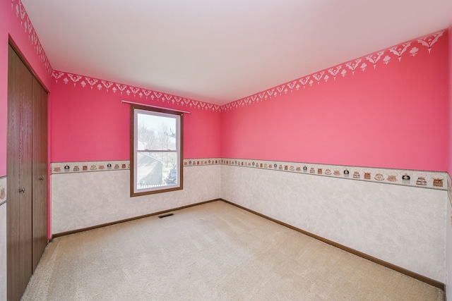 carpeted empty room featuring visible vents, baseboards, and wallpapered walls