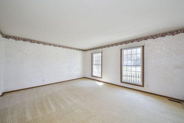 spare room with visible vents, light colored carpet, and baseboards