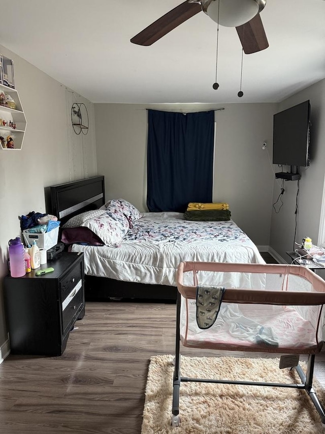 bedroom featuring ceiling fan, baseboards, and wood finished floors