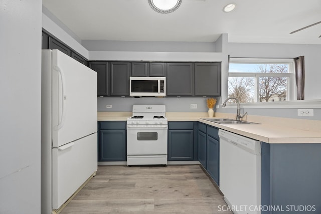 kitchen with light wood-style flooring, a sink, recessed lighting, white appliances, and light countertops