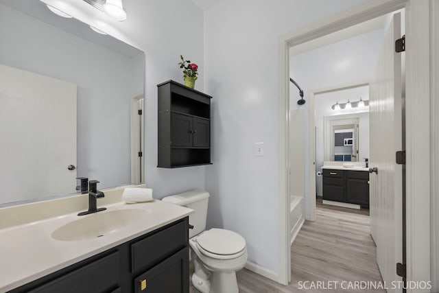 bathroom featuring wood finished floors, a sink, shower / bath combination, toilet, and two vanities