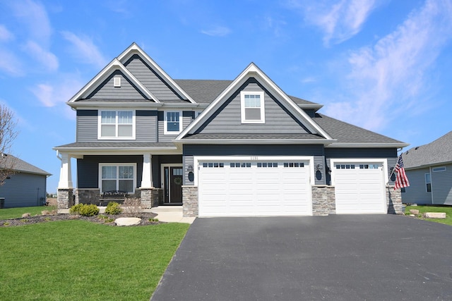 craftsman house featuring an attached garage, a front lawn, stone siding, and aphalt driveway