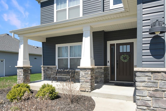 view of exterior entry featuring a porch and stone siding