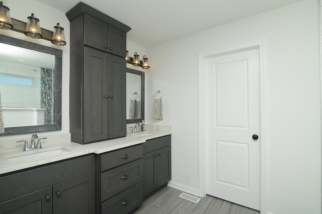 bathroom with baseboards, double vanity, a sink, and visible vents