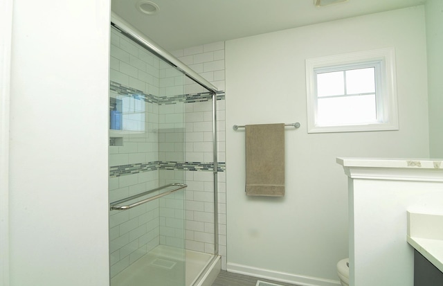 full bath with toilet, vanity, baseboards, and a stall shower