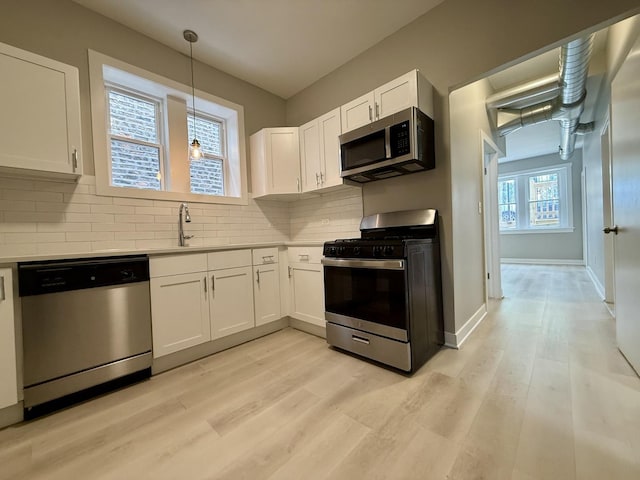 1824 W 22nd Pl, Chicago, IL 60608 - kitchen featuring appliances with stainless steel finishes, light wood-style flooring, white cabinets, light countertops, and decorative backsplash