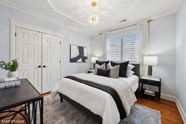 bedroom featuring visible vents, baseboards, a closet, a chandelier, and wood finished floors