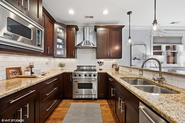kitchen with wall chimney exhaust hood, tasteful backsplash, visible vents, a sink, and stainless steel appliances