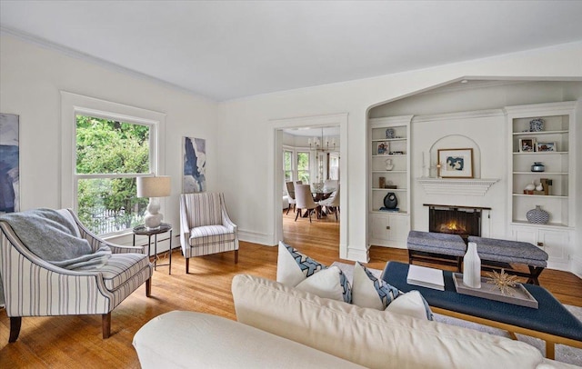 820 Lake Ave, Wilmette, IL 60091 - living room featuring wood finished floors, a chandelier, crown molding, a lit fireplace, and baseboards