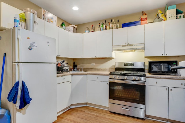 1234 S Karlov Ave, Chicago, IL 60623 - kitchen featuring freestanding refrigerator, stainless steel range with gas cooktop, under cabinet range hood, black microwave, and light wood finished floors